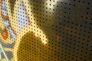 Close-up a metal surface with many holes between it and different colors smeared on the surface creates a beautiful pattern in a vintage tone background. photo