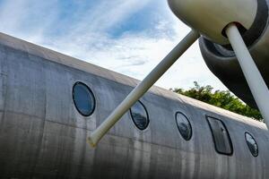 Front view of airplane body and propeller engine is an old commercial airplane that is no longer in use showing the surface of silver metal and parts. photo