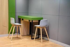 Modern style interior design with gray and green wall with two office chairs and wooden table on wood pattern floor with soft light for concept of work desk and relaxing room. photo