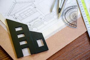 Home architectural design plan with lines or sketches and miniature black building model using pencil and ruler drawing tools for engineer's blueprint design. photo
