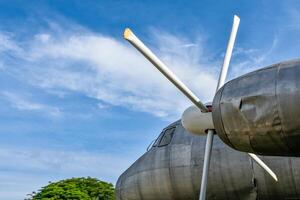 View of old and rusted airplane head parts and engine propellers parked in the parking lot against the background of forest and blue sky. photo