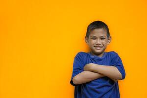 Cute boy smiling and is using both hands to fold his arms around his chest or cross one's arm are ready to fight in an isolated light yellow color studio background. photo