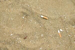 Cigarette butts left on the sand at the beach have a negative effect on the marine environment in a vintage tone background. photo