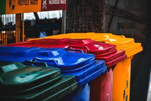 Trash cans of various colors are public garbage dumps at beachside area is used for dumping garbage and separating hazardous waste in the dark tone background. Recycle waste. photo