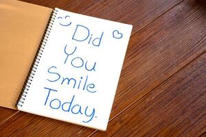 Text of Did You Smile Today write on the white paper of the notebook an encouraging article or question. photo