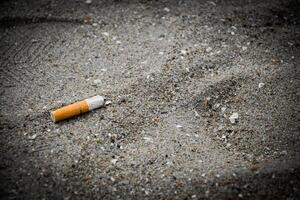 Fag-End or Cigarette butts on the sand at the beach side have a negative effect on the marine environment for no smoking concept on a dark vintage tone background. photo