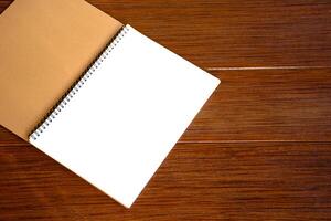 Empty open blank white notebook or blank white paper on a brown wooden plank background with a beautiful pattern. photo