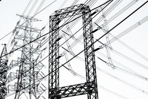 Black lines and steel structure of high-voltage poles and electrical wires transmitting electrical energy from a power plant on a white isolated background. photo