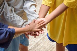 Top view group of children diverse hands together joining team for teamwork. Young people touch hands for a unity group of students. photo