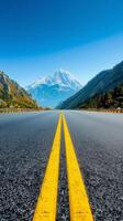 Empty Road Leading to Snowy Mountain Peak in Valley Landscape. photo