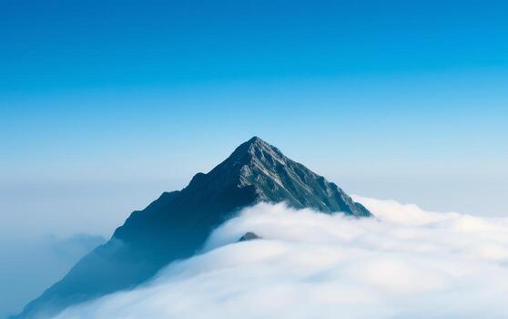 Mountain Peak Emerging Through Clouds With Blue Sky In Background. photo