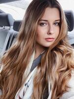 Young woman with long hair, wavy hairstyle in the car or taxi cab as passenger, exploring the city, transport and travel photo