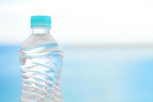 bottle of water on the beach - drinks, summertime and environment concept photo