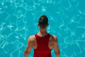 Lifeguard in a bright red tank top standing by the crystal clear waterpool, alert and watchful photo