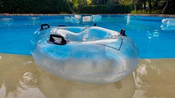 Transparent inflatable swimming ring floating in a resort pool, symbolizing leisure 15 feb 2024, Vietnam, Pho quoc travel and summer vacations, with lush greenery backdrop photo
