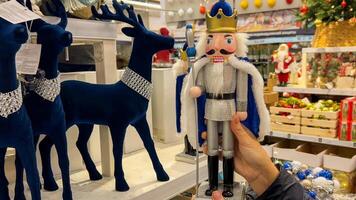Hand holding traditional nutcracker figurine in a Christmas holiday shop with festive decorations and reindeer models, suggesting holiday shopping and seasonal decor 15 dec 2023, Shanghai, China photo
