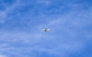 Passenger airplane flies in blue sky with clouds in Mexico. photo