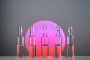 Several ampoules for injection with medicines on a pink background. photo