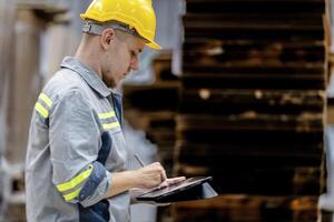 man worker walking and checking stock items for shipping. male inspecting the store factory. Logistics employees holding folders at on site warehouse area for shipping transportation. photo