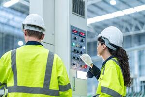 Male and female engineers in neat work clothes prepare and control the production system of large modern machines in a factory producing industrial technology products. photo