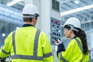 Male and female engineers in neat work clothes prepare and control the production system of large modern machines in a factory producing industrial technology products. photo