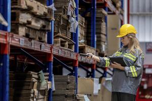 woman worker walking and checking stock items for shipping. Female inspecting the store factory. Logistics employees holding folders at on site warehouse area for shipping transportation. photo