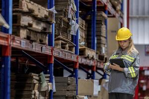 woman worker walking and checking stock items for shipping. Female inspecting the store factory. Logistics employees holding folders at on site warehouse area for shipping transportation. photo