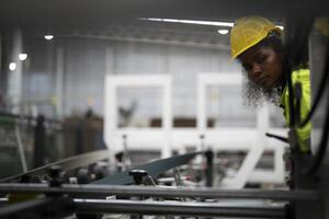 Portrait of African woman worker beautiful face with eye confident and wearing working suite dress and safety helmet at heavy machine in industry factory. Engineer worker concentrate on workplace. photo