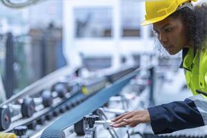 Portrait of African woman worker beautiful face with eye confident and wearing working suite dress and safety helmet at heavy machine in industry factory. Engineer worker concentrate on workplace. photo