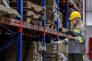 woman worker walking and checking stock items for shipping. Female inspecting the store factory. Logistics employees holding folders at on site warehouse area for shipping transportation. photo