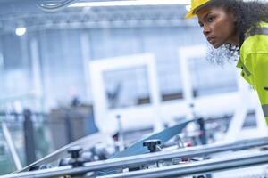 Portrait of African woman worker beautiful face with eye confident and wearing working suite dress and safety helmet at heavy machine in industry factory. Engineer worker concentrate on workplace. photo