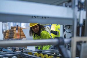 Portrait of African woman worker beautiful face with eye confident and wearing working suite dress and safety helmet at heavy machine in industry factory. Engineer worker concentrate on workplace. photo