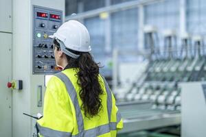 Male and female engineers in neat work clothes prepare and control the production system of large modern machines in a factory producing industrial technology products. photo