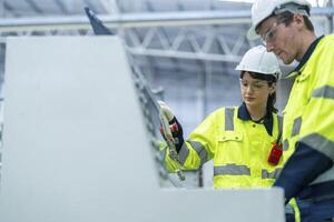 Male and female engineers in neat work clothes prepare and control the production system of large modern machines in a factory producing industrial technology products. photo
