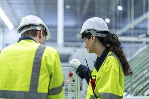 Male and female engineers in neat work clothes prepare and control the production system of large modern machines in a factory producing industrial technology products. photo
