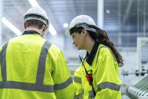 Male and female engineers in neat work clothes prepare and control the production system of large modern machines in a factory producing industrial technology products. photo