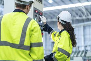 Male and female engineers in neat work clothes prepare and control the production system of large modern machines in a factory producing industrial technology products. photo