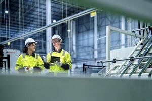 Male and female engineers in neat work clothes prepare and control the production system of large modern machines in a factory producing industrial technology products. photo