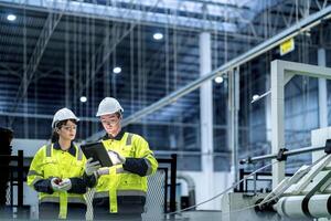 Male and female engineers in neat work clothes prepare and control the production system of large modern machines in a factory producing industrial technology products. photo