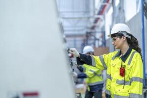 Male and female engineers in neat work clothes prepare and control the production system of large modern machines in a factory producing industrial technology products. photo
