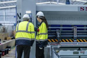 Male and female engineers in neat work clothes prepare and control the production system of large modern machines in a factory producing industrial technology products. photo