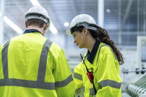 Male and female engineers in neat work clothes prepare and control the production system of large modern machines in a factory producing industrial technology products. photo