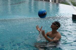 Asian men practicing swimming and preparing to play water polo and stretching and resting for water sports. photo