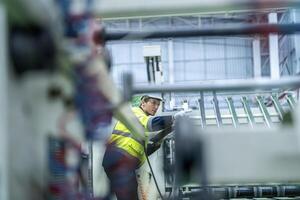 Male and female engineers in neat work clothes prepare and control the production system of large modern machines in a factory producing industrial technology products. photo