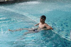 Asian men practicing swimming and preparing to play water polo and stretching and resting for water sports. photo