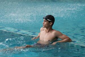Asian men practicing swimming and preparing to play water polo and stretching and resting for water sports. photo