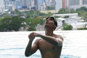 Asian men practicing swimming and preparing to play water polo and stretching and resting for water sports. photo