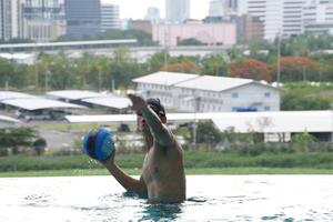 Asian men practicing swimming and preparing to play water polo and stretching and resting for water sports. photo