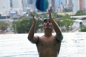 Asian men practicing swimming and preparing to play water polo and stretching and resting for water sports. photo