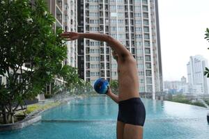Asian men practicing swimming and preparing to play water polo and stretching and resting for water sports. photo
